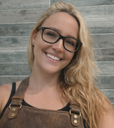 Sheila sonríe a cámara con gafas y delantal de cuero marrón